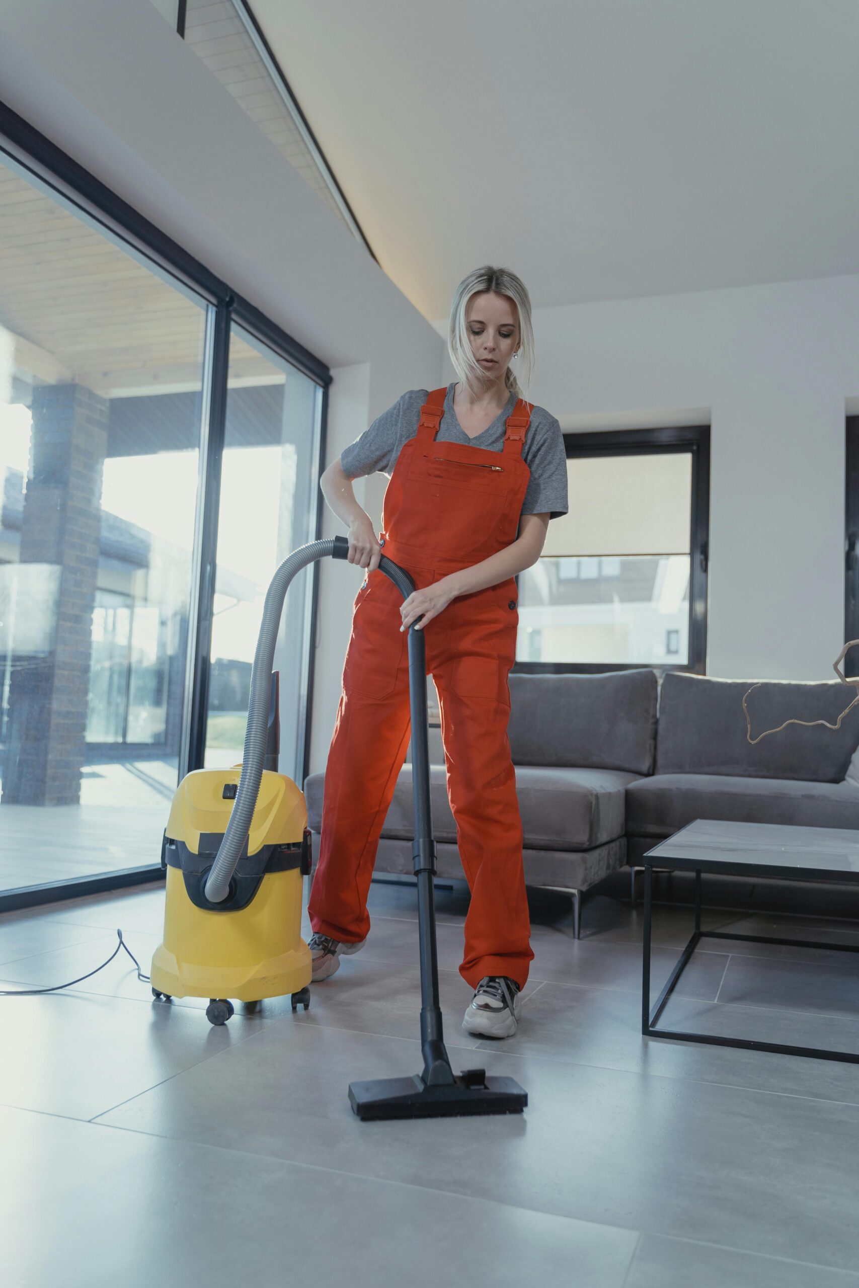 a woman of Luminex Cleaning in orange jumpsuit vacuuming a floor | Residential Cleaning | used for luminexcleaning.nl