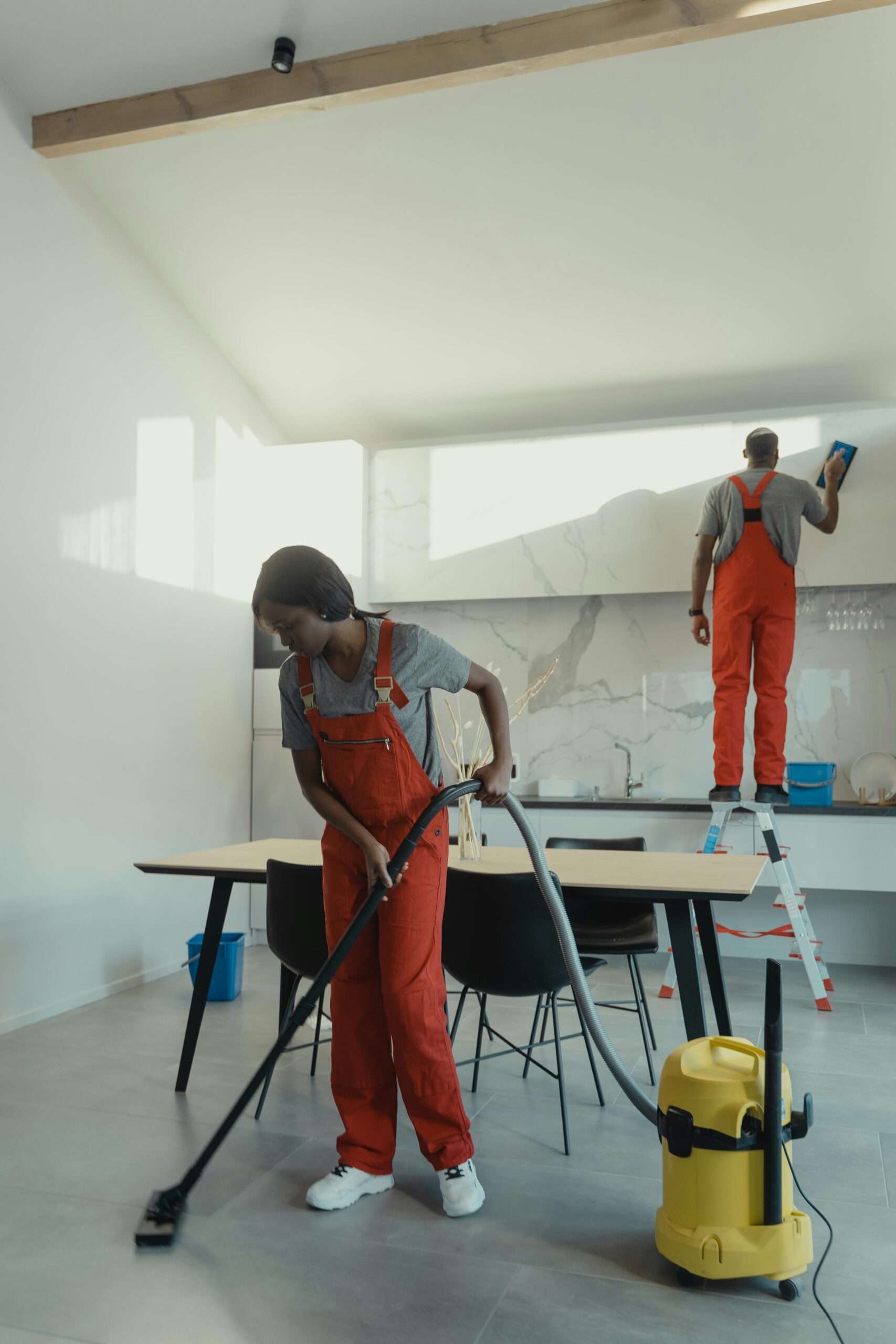 a woman of Luminex Cleaning in orange jumpsuit vacuuming a floor | Residential Cleaning | used for luminexcleaning.nl