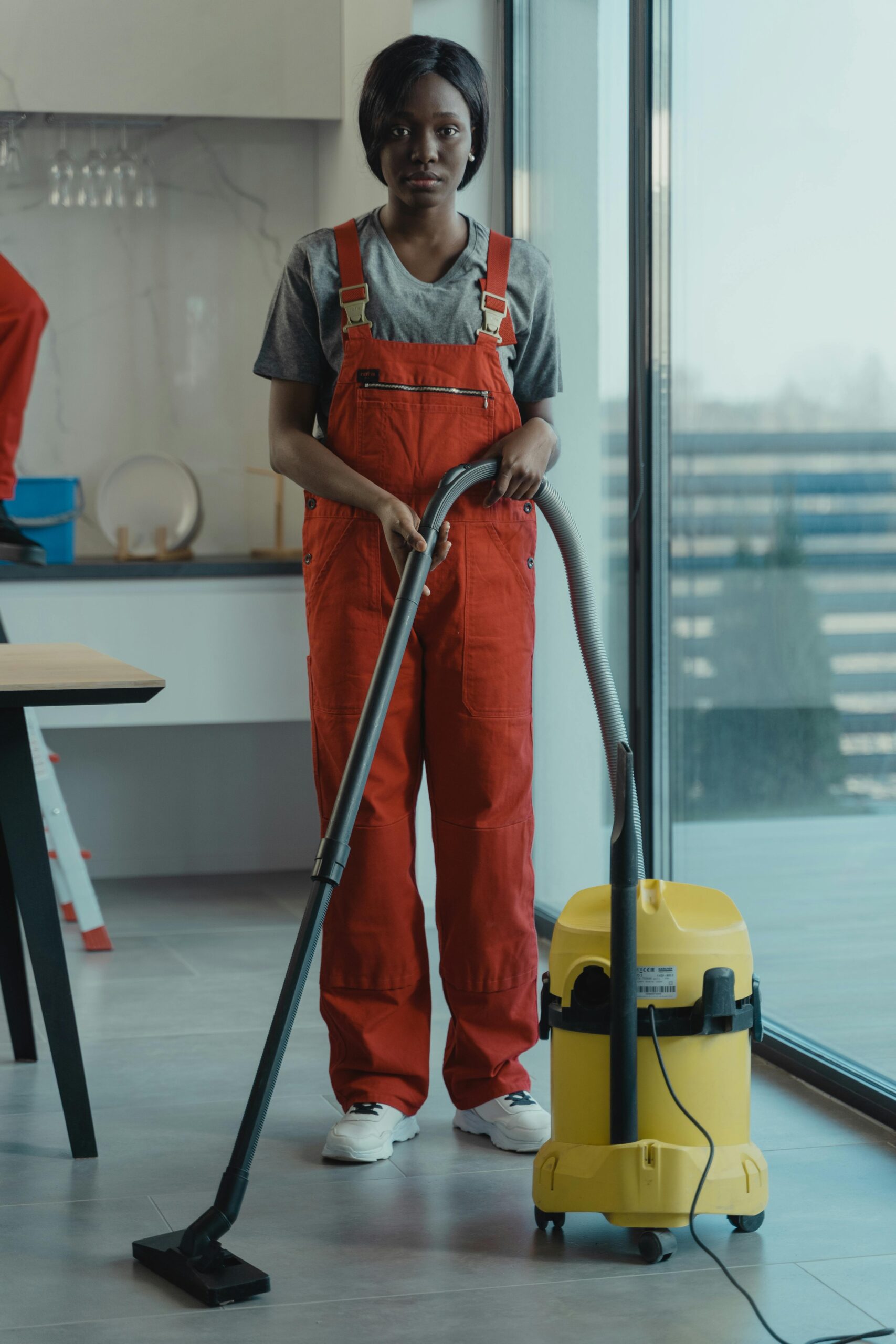 a woman of Luminex Cleaning in orange jumpsuit vacuuming a floor | Residential Cleaning | used for luminexcleaning.nl