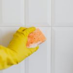 a hand in yellow glove holding a sponge