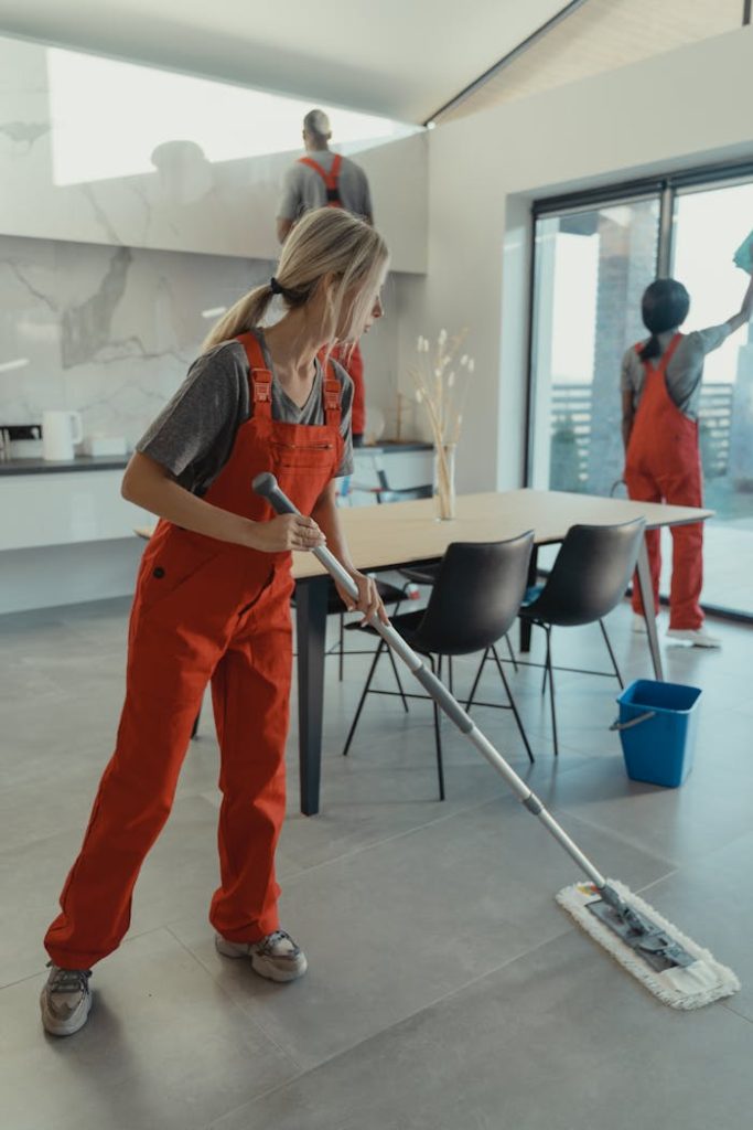 a woman of Luminex Cleaning in orange jumpsuit vacuuming a floor | Residential Cleaning | used for luminexcleaning.nl