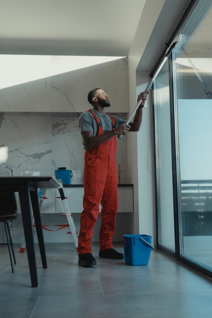 a man of Luminex Cleaning in red overalls cleaning a window | Residential Cleaning | used for luminexcleaning.nl